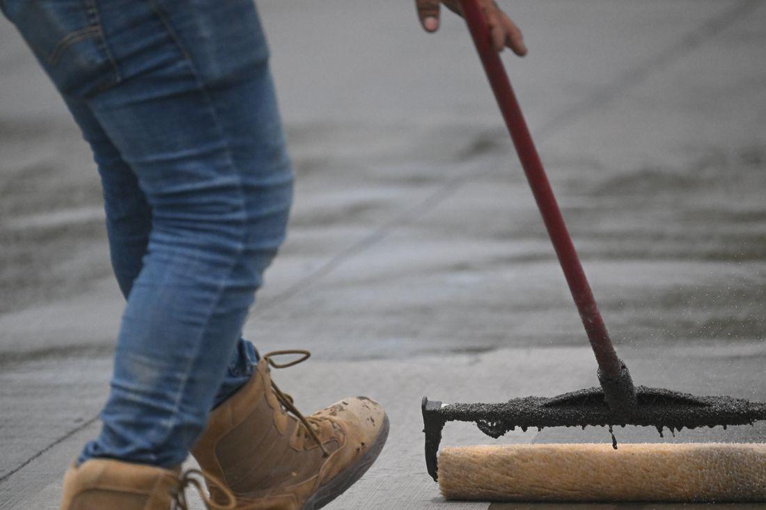 A squeegee spreading sealer across pavement