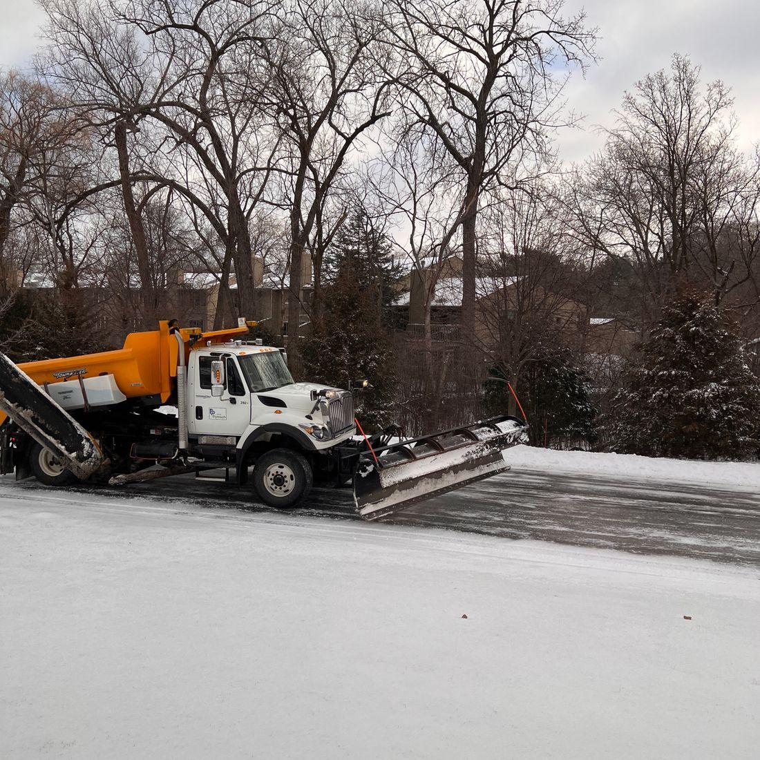 A plow truck clearing snow on a residential road