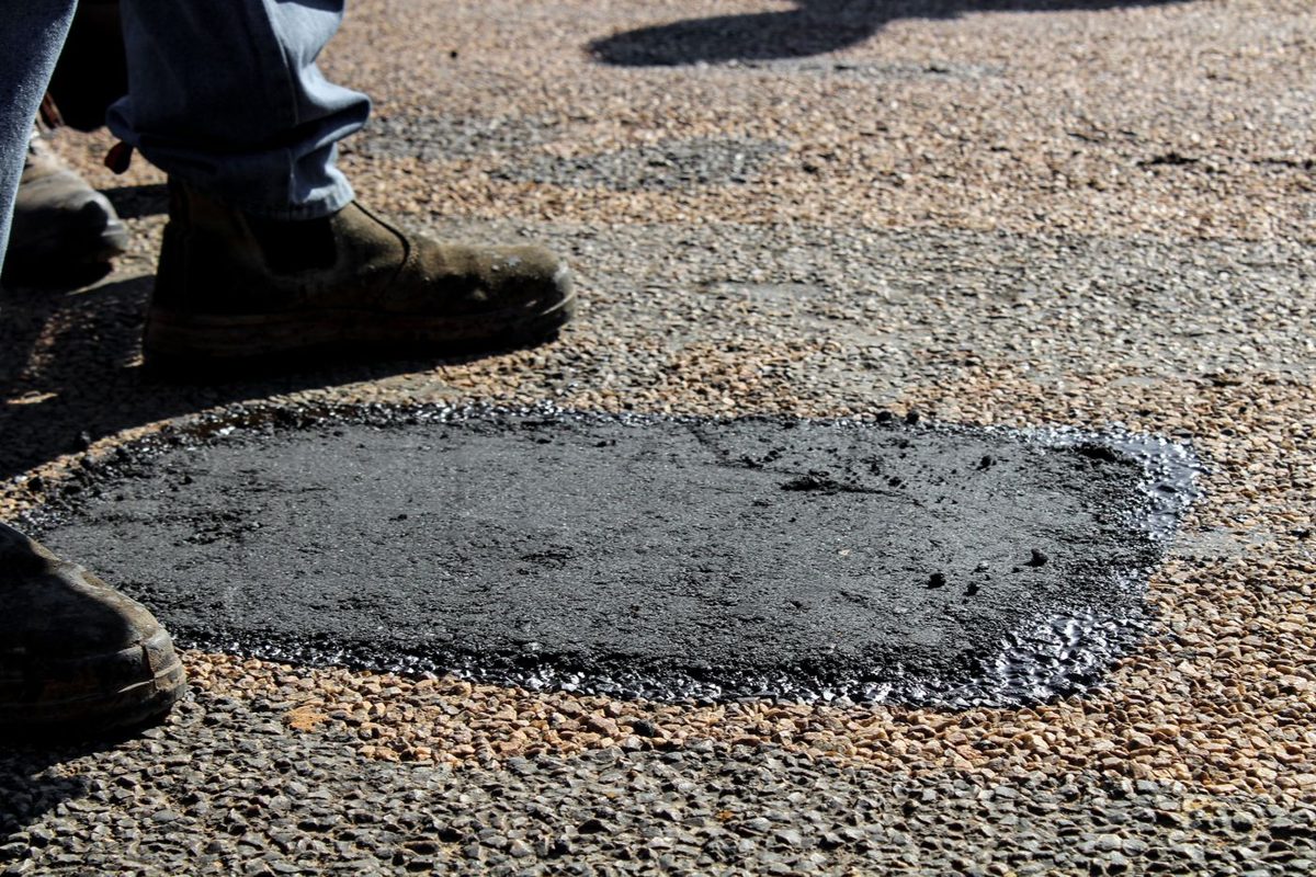 A fresh asphalt patch filling a damaged section of pavement