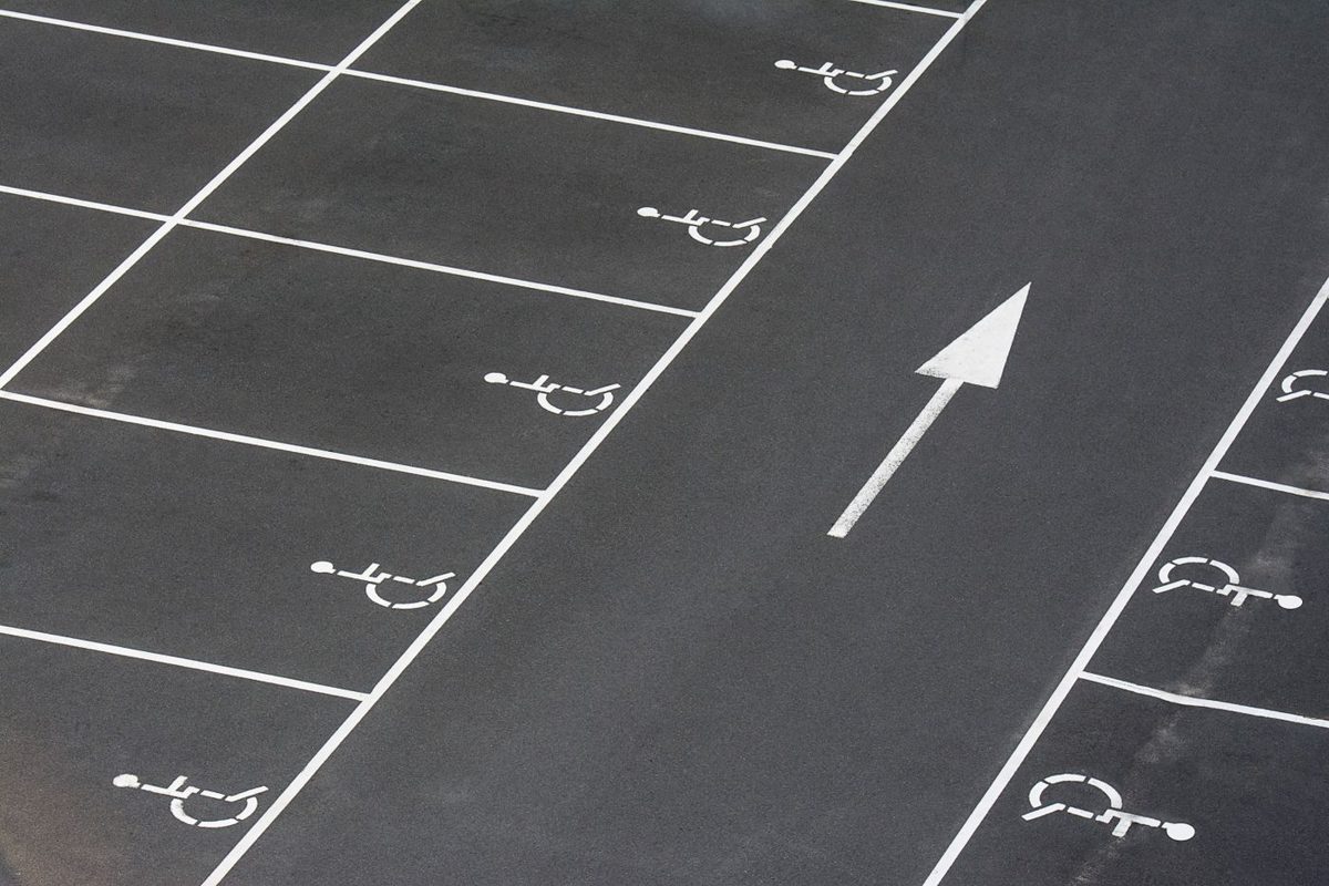 Fresh white parking lot lines and a direction arrow on dark asphalt